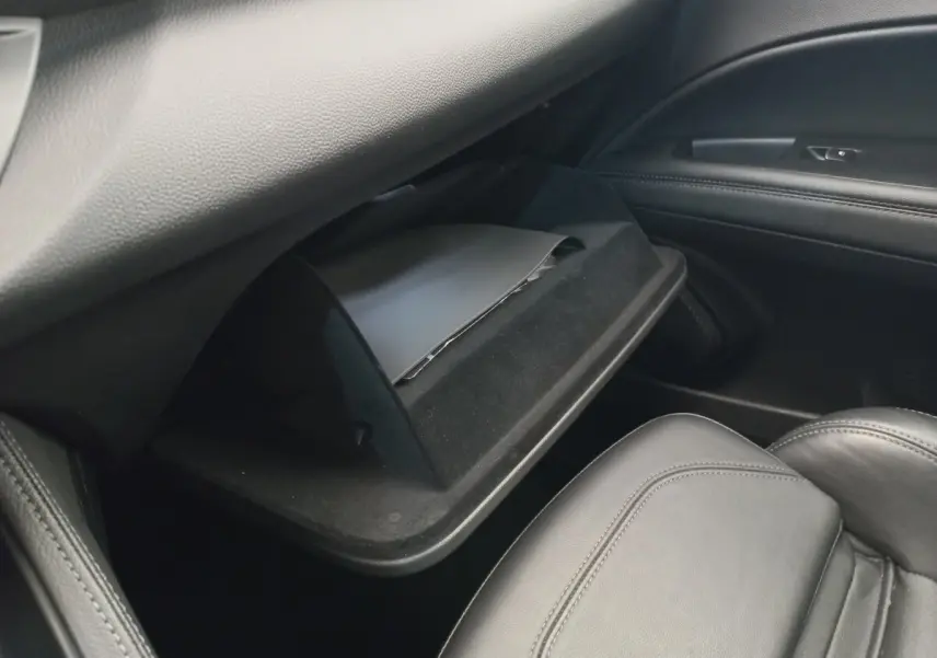 Vue intérieure côté passager de la boîte à gants ouverte avec revêtement noir dans l'Alfa Romeo Stelvio gris foncé.
