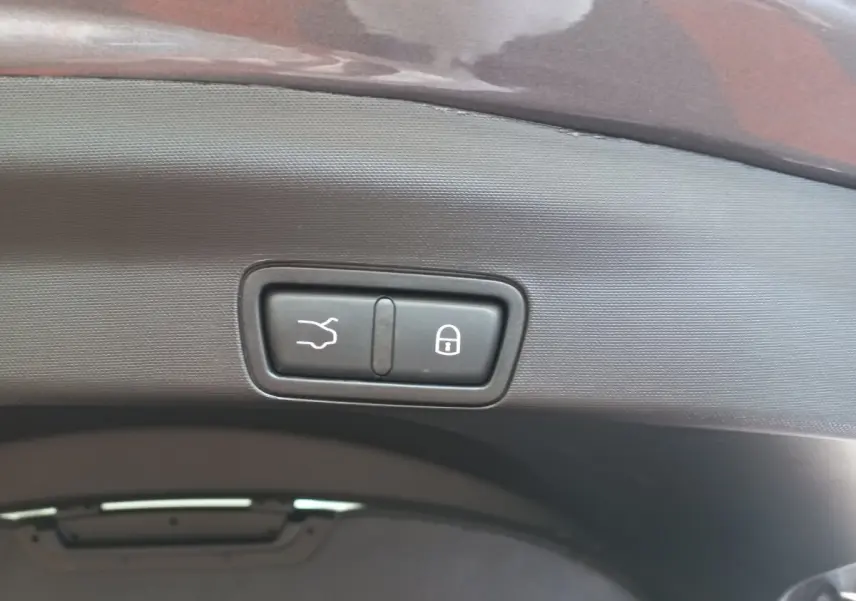 Gros plan sur les boutons d'ouverture et de verrouillage du coffre d'un Alfa Romeo Stelvio gris foncé, vue intérieure arrière.