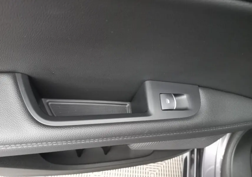 Détail de la poignée intérieure de porte côté gauche en cuir noir avec bouton de verrouillage, Alfa Romeo Stelvio gris foncé.