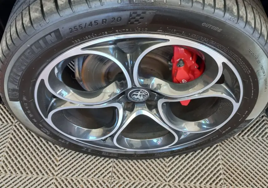 Gros plan sur la roue avant droite de l'Alfa Romeo Stelvio gris foncé, avec étrier de frein rouge visible.
