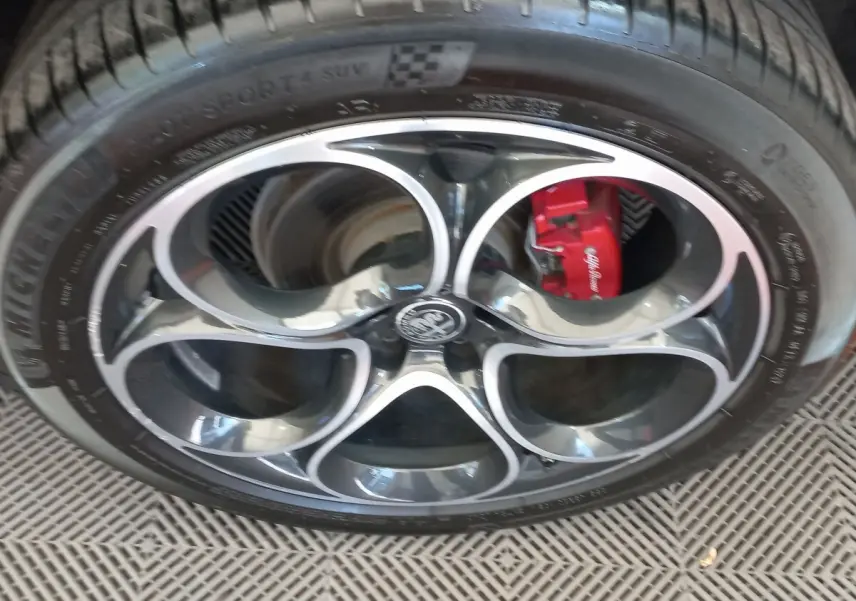 Gros plan sur la jante alu noire et argentée d’un Alfa Romeo Stelvio 2024 avec étrier de frein rouge visible.