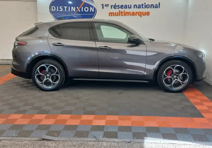 Vue de profil côté gauche d’un Alfa Romeo Stelvio gris foncé avec jantes distinctives et étriers de frein rouges.