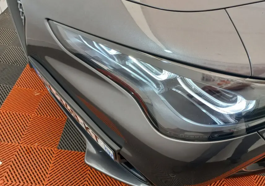 Gros plan sur le phare avant droit d'un Alfa Romeo Stelvio gris foncé 2024 avec détails lumineux LED distinctifs.