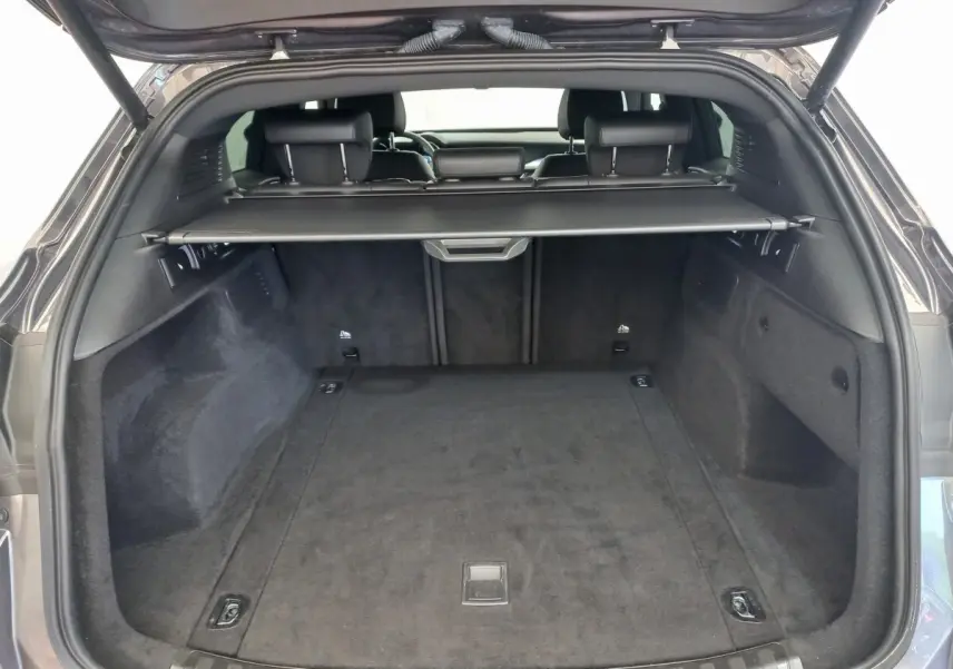 Coffre ouvert vu de l'arrière d'un Alfa Romeo Stelvio gris foncé, avec cache-bagages et banquette arrière visible.