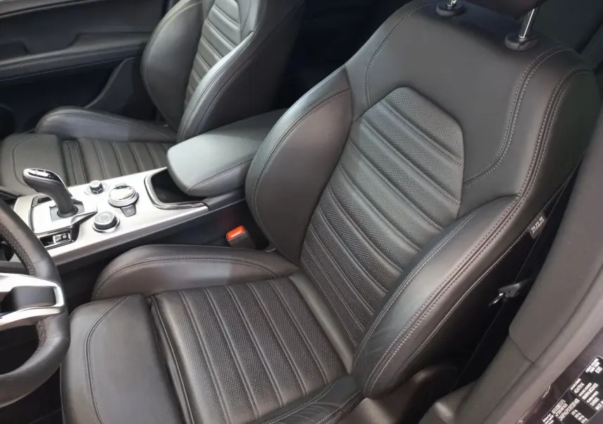 Vue intérieure rapprochée des sièges avant en cuir noir de l'Alfa Romeo Stelvio 2.2 TD 160 AT8 Sprint, avec console centrale visible.