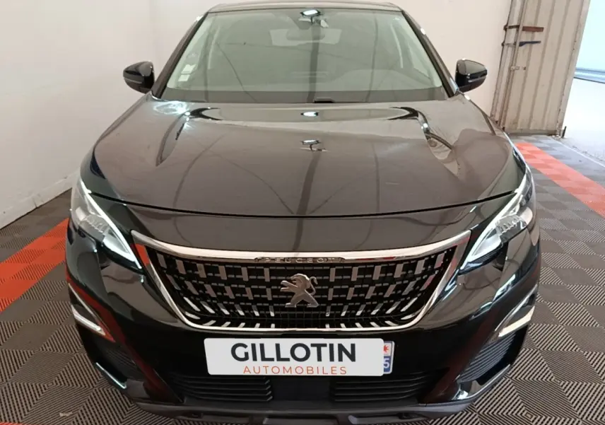 Vue avant d’un Peugeot 3008 noir avec calandre chromée et phares LED, stationné en intérieur sur sol damier.