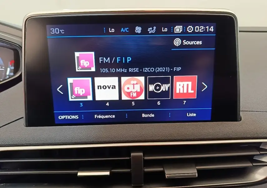 Écran tactile central du tableau de bord du Peugeot 3008 noir, affichant les stations radio FM en mode nuit.