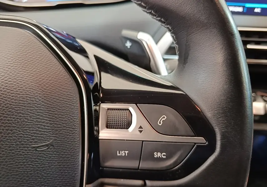 Gros plan sur le volant cuir noir multifonctions du Peugeot 3008, avec commandes audio et téléphone intégrées.