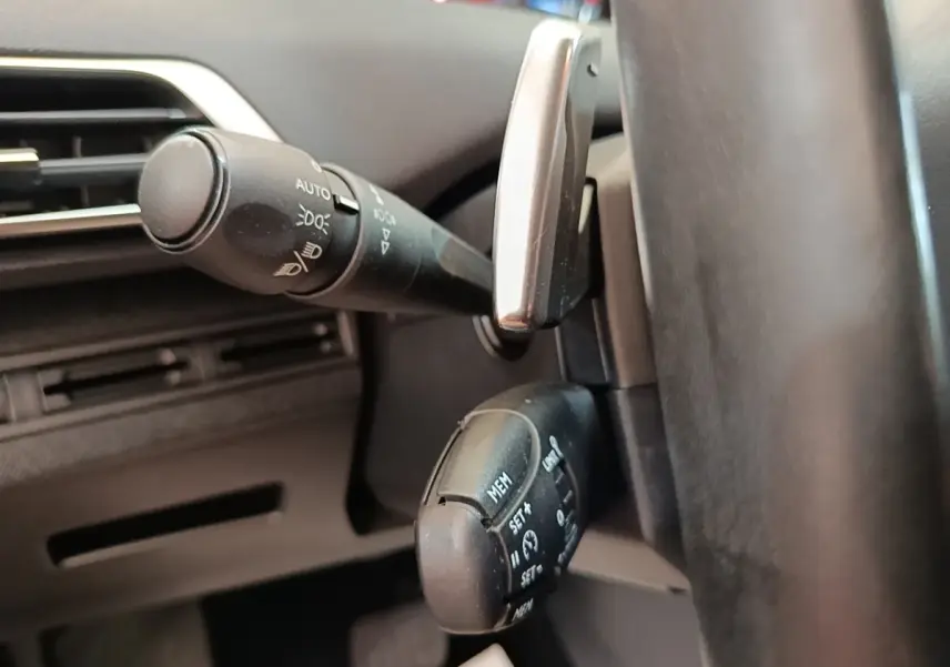Gros plan sur les commandes au volant cuir noir du Peugeot 3008, avec levier de clignotants et régulateur de vitesse.