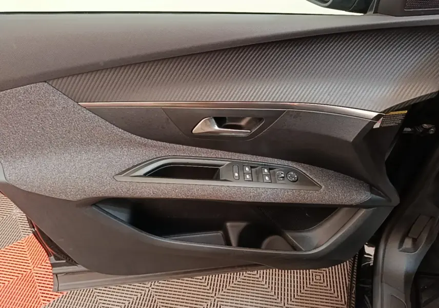 Vue intérieure du panneau de porte avant gauche du Peugeot 3008 noir, avec commandes des vitres et poignée intégrée.