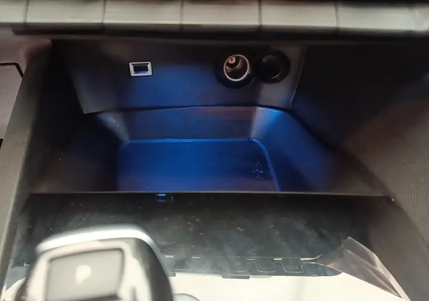 Gros plan sur la console centrale noire du Peugeot 3008, avec prise USB et allume-cigare visibles.