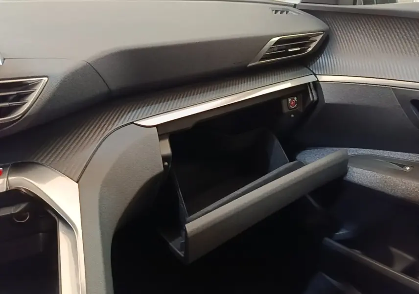 Vue intérieure côté passager du Peugeot 3008 2018 noir, boîte à gants ouverte et tableau de bord avec finition carbone.