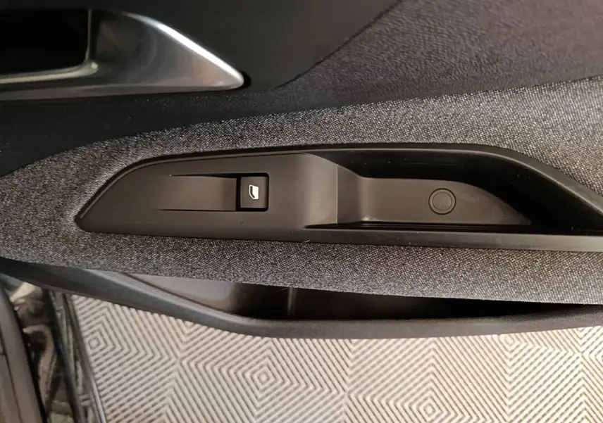 Détail de la commande de lève-vitre sur la porte côté conducteur d’un Peugeot 3008 noir, intérieur tissu gris.