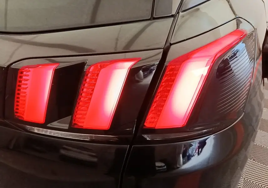 Gros plan sur le feu arrière droit rouge du Peugeot 3008 noir, soulignant la carrosserie brillante.