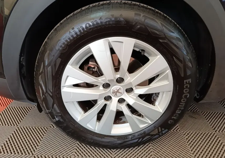 Gros plan sur la roue avant droite d’un Peugeot 3008 noir, avec jante alliage argentée et pneu Continental.