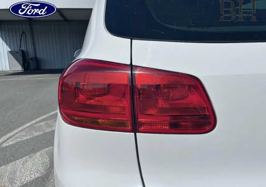 Gros plan sur le feu arrière gauche d’un Volkswagen Tiguan blanc Candy, vue arrière côté gauche.