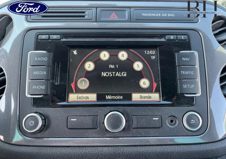 Tableau de bord noir avec écran tactile central affichant la radio, dans un Volkswagen Tiguan blanc Candy 2013.
