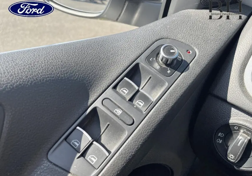Gros plan sur la commande des vitres électriques côté conducteur d’un Volkswagen Tiguan, intérieur noir texturé.