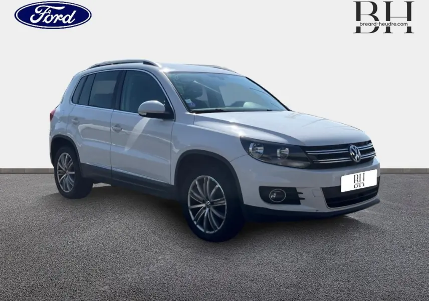 Volkswagen Tiguan blanc Candy vu en 3/4 avant droit avec jantes alu 17 pouces et barres de toit.
