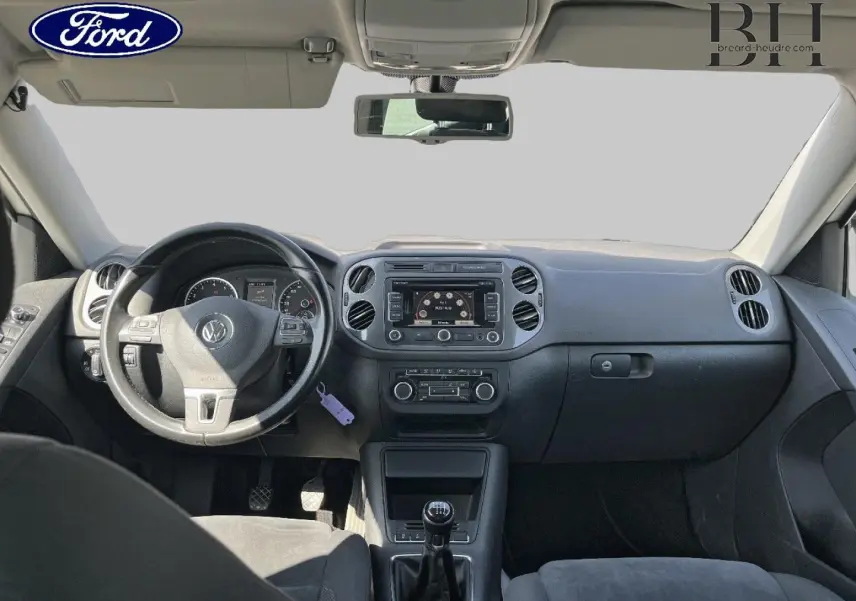 Vue intérieure avant du tableau de bord et volant noir d'un Volkswagen Tiguan 2013, avec écran central et commandes visibles.