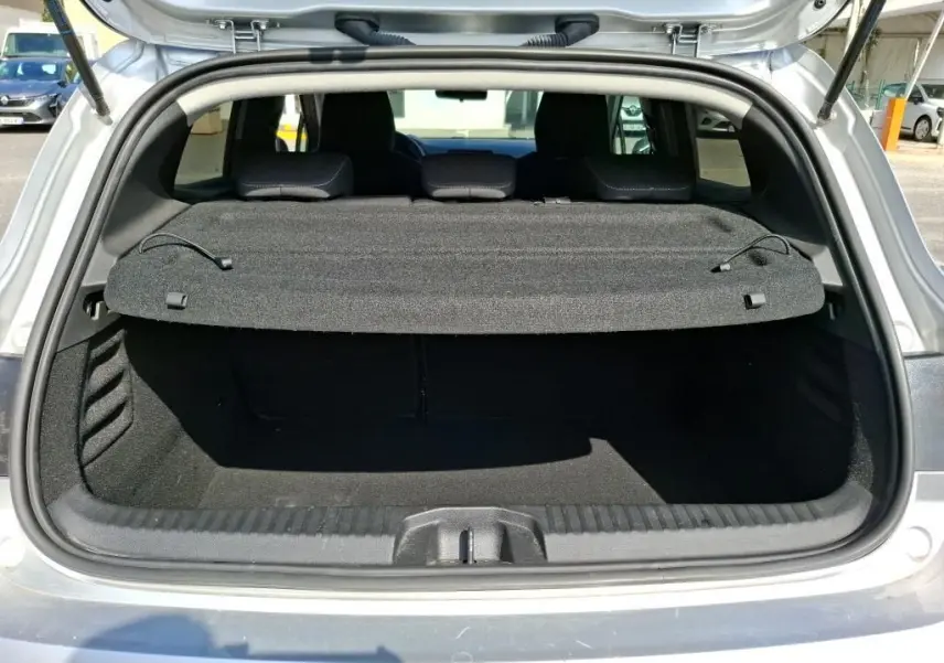 Coffre ouvert vu de l'arrière d'une Renault Clio gris platine 2023, avec cache-bagages en place.
