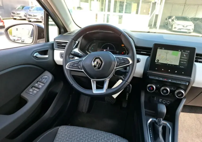 Vue intérieure avant du tableau de bord et volant noir d’une Renault Clio 1.6 E-Tech gris platine avec écran tactile et commandes digitales.