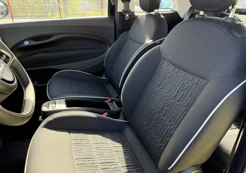 Vue intérieure côté droit de la Fiat 500 e 118ch MY24 avec sièges noirs monogramme Fiat et surpiqûres blanches.