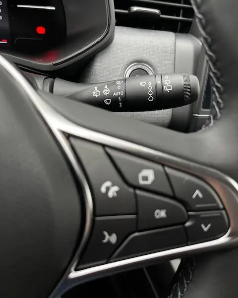 Gros plan sur les commandes au volant et le commodo d'essuie-glace d'une Renault Clio noire, version Evolution Blue dCi 100.