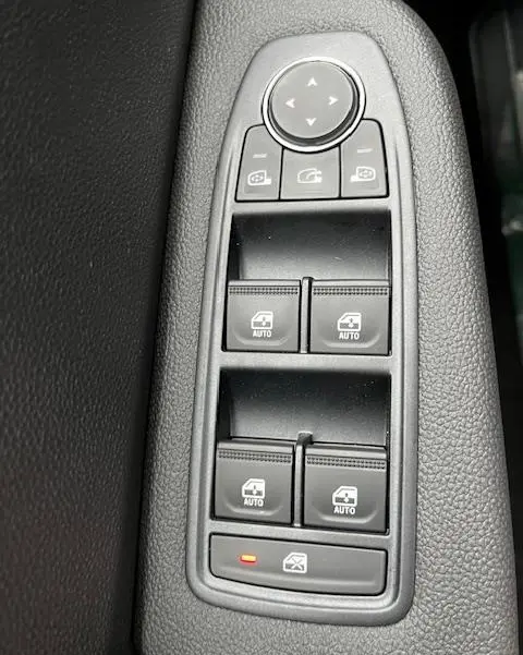 Vue rapprochée des commandes de lève-vitres et rétroviseurs sur la porte côté conducteur d’une Renault Clio noire 2025.