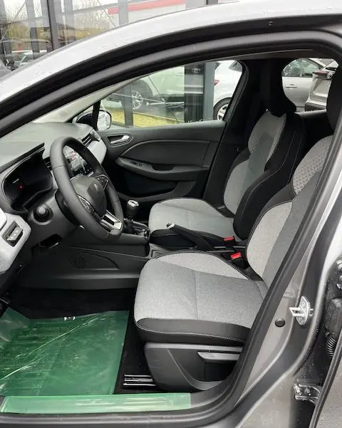 Vue intérieure côté conducteur de la Renault Clio 2025, sièges gris clair avec volant multifonctions en cuir noir.