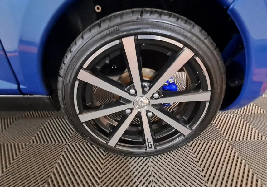 Gros plan sur la roue avant droite de l’AIXAM Ambition bleu avec jante noire et argentée au design moderne.