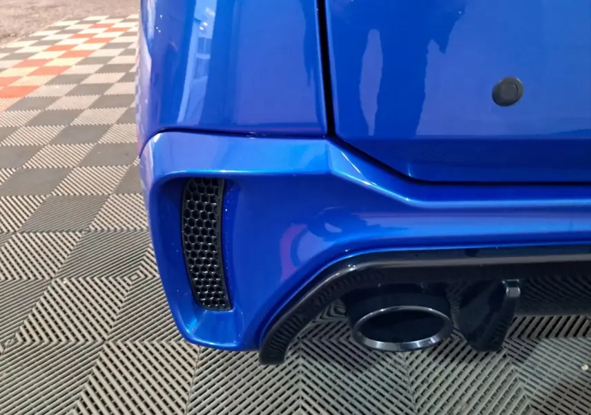 Gros plan sur le coin arrière droit bleu d'une Aixam Ambition 2026, avec sortie d'échappement et prise d'air noire.