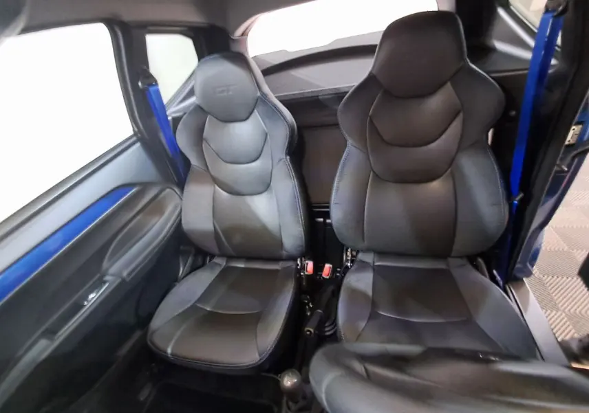 Vue intérieure des sièges avant noirs de l'AIXAM AMBITION 0.5 CITY GTO avec ceinture bleue côté gauche.
