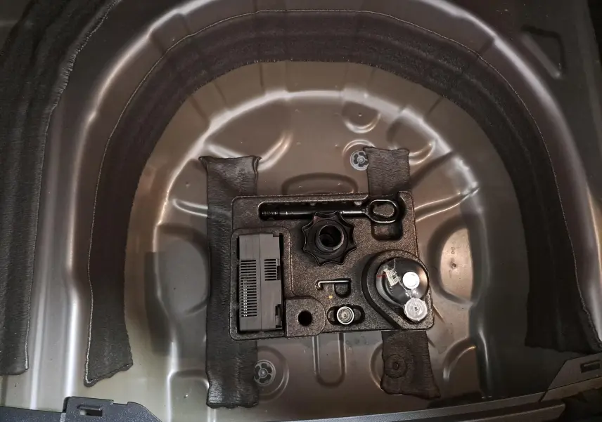 Gros plan sur le rangement sous le coffre du Volkswagen Taigo 1.5 TSI 150 DSG7 R-Line Edition, montrant l’outillage d’origine.