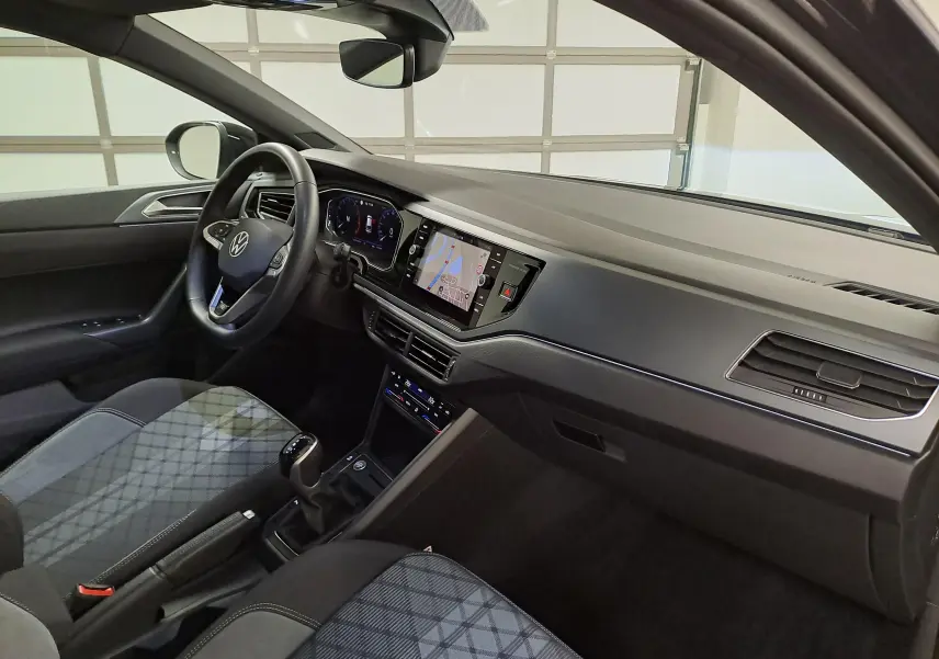 Vue intérieure côté conducteur du Volkswagen Taigo 1.5 TSI 150 DSG7 R-Line Edition avec tableau de bord numérique et sièges à motif gris.