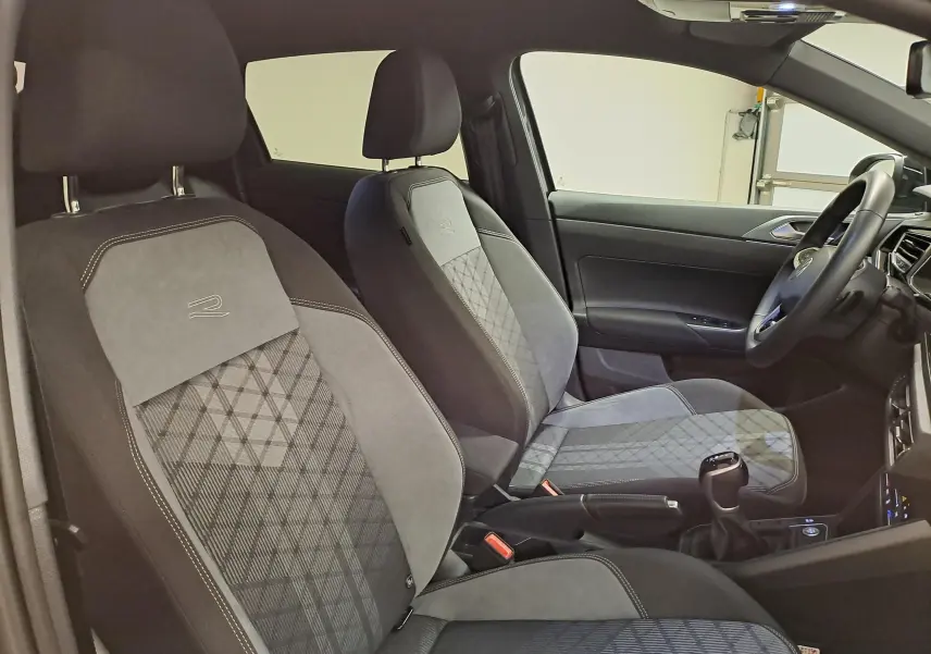Vue intérieure côté conducteur du Volkswagen Taigo 1.5 TSI R-Line 2025, sièges tissu gris à motif géométrique et logo R brodé.