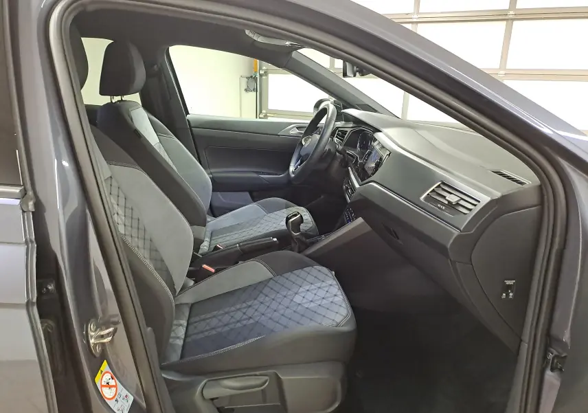 Vue intérieure côté conducteur du Volkswagen Taigo 1.5 TSI 150 DSG7 R-Line Edition 2025, sièges tissu gris et tableau de bord noir.