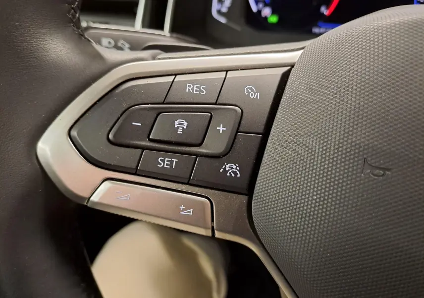 Gros plan sur les commandes au volant du Volkswagen Taigo 1.5 TSI R-Line 2025, boutons de régulateur de vitesse et assistance.