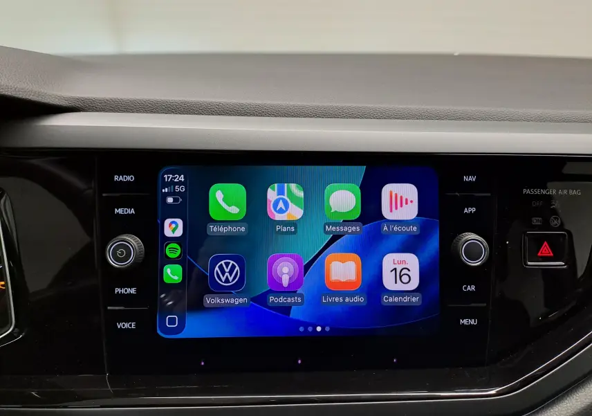 Écran tactile central du Volkswagen Taigo 2025 affichant les applications connectées, entouré de commandes noires brillantes.