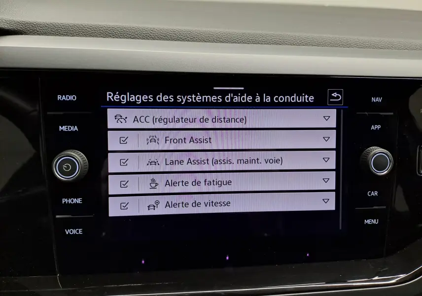 Écran tactile intérieur du Volkswagen Taigo 2025 affichant les réglages des aides à la conduite, boutons autour de l'écran.