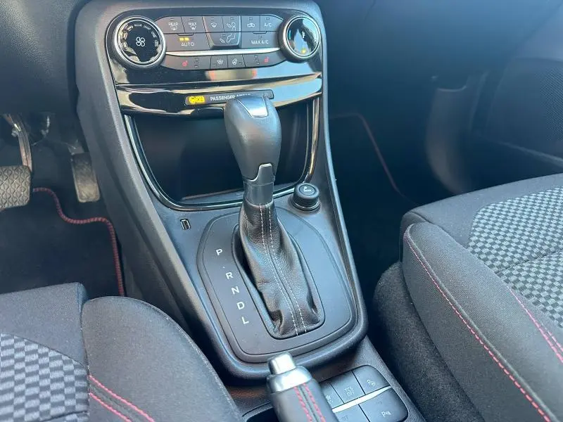 Gros plan sur la console centrale du Ford Puma 2024 gris Solar, montrant le levier de vitesse et les commandes climatisation.