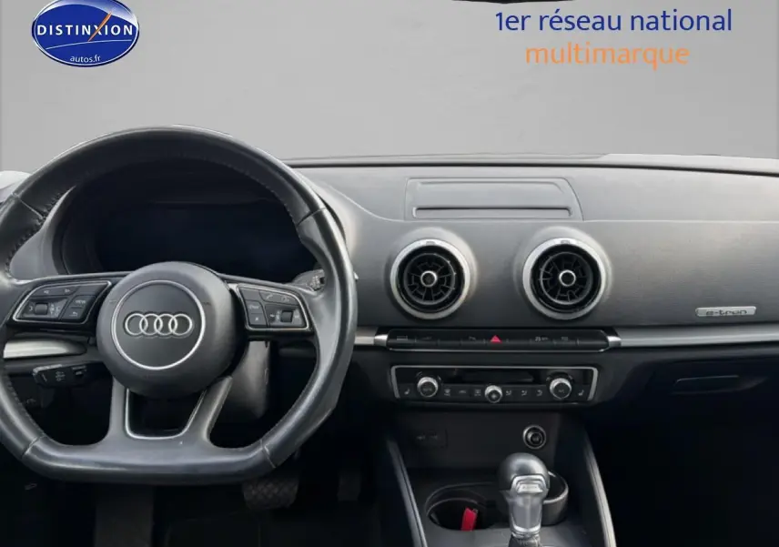 Vue intérieure du tableau de bord et volant noir d'une Audi A3 Sportback 40 e-tron, avec aérateurs ronds et badge e-tron.