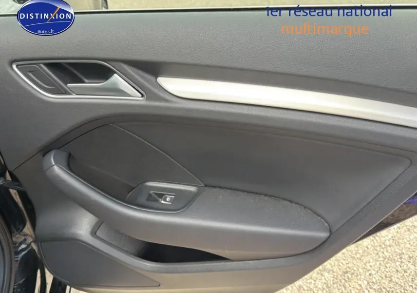 Vue intérieure du panneau de porte côté gauche noir de l'Audi A3 Sportback 40 e-tron avec poignée et commande de fenêtre électrique.