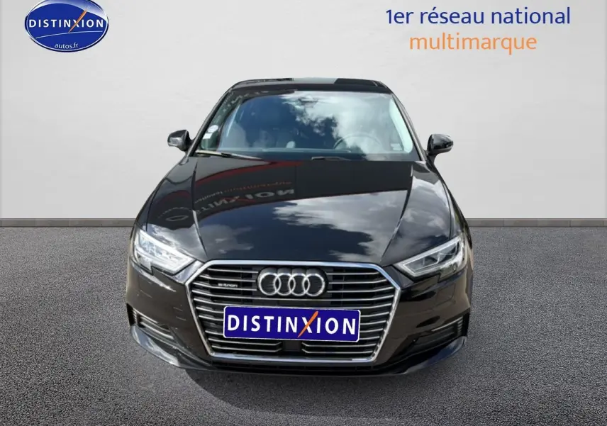Vue avant d'une Audi A3 Sportback noire avec calandre chromée et phares LED, stationnée sur sol gris.
