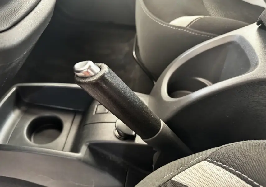 Gros plan intérieur sur le frein à main et porte-gobelets entre les sièges avant noirs du Renault Kangoo blanc.