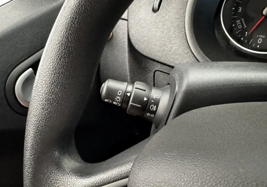 Gros plan sur le commodo d’éclairage à gauche du volant noir dans l’habitacle du Renault Kangoo blanc 2016.