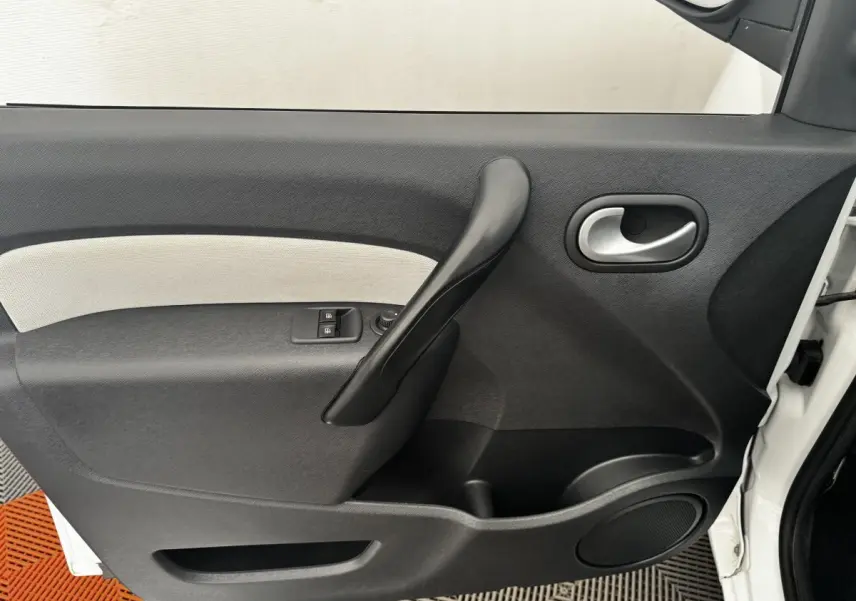 Vue rapprochée de la porte avant droite blanche du Renault Kangoo Zen 2016 avec poignée noire et commandes de vitres.