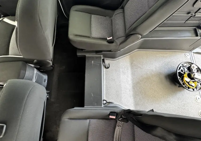 Vue plongeante sur l’intérieur arrière du Renault Kangoo 2016, sièges noirs et plancher partiellement découvert.