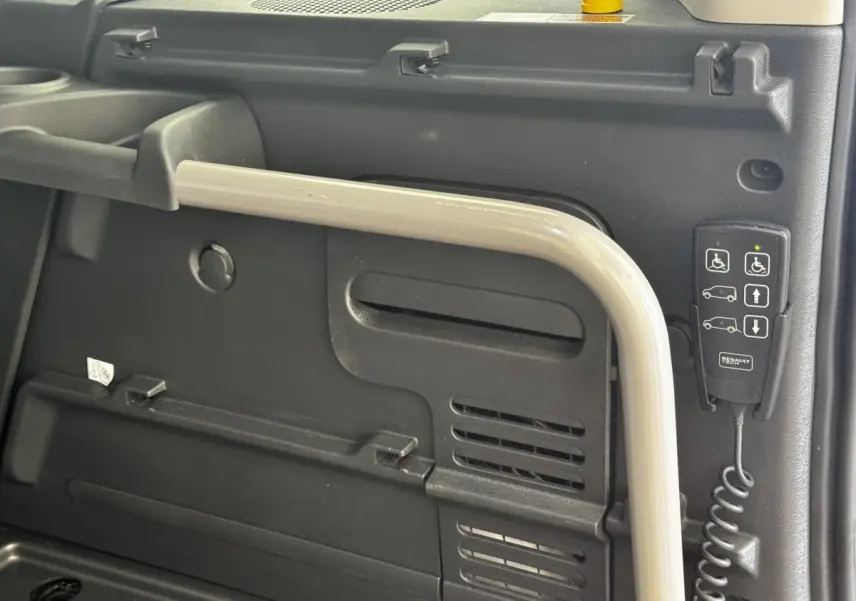 Détail intérieur montrant la commande d’accessibilité et la poignée de maintien dans un Renault Kangoo blanc 2016.