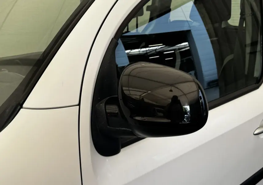 Gros plan sur le rétroviseur noir côté conducteur d’un Renault Kangoo blanc, vue latérale avant.
